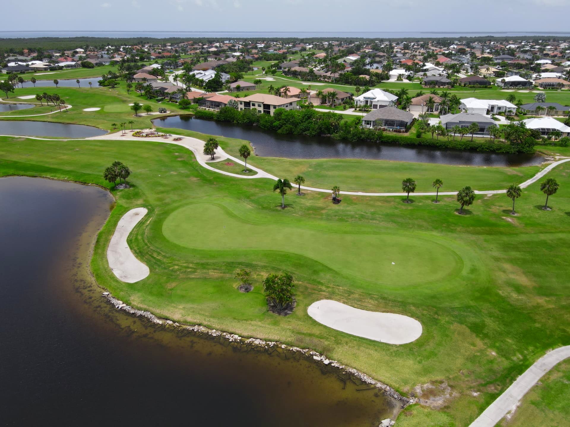 Aerial view of a green guarded by water and white sand bunkers